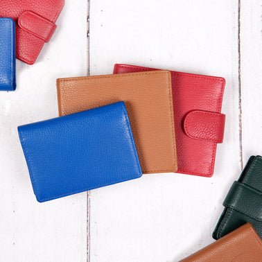 Three men's wallets in blue, brown and red on a white wooden background. 