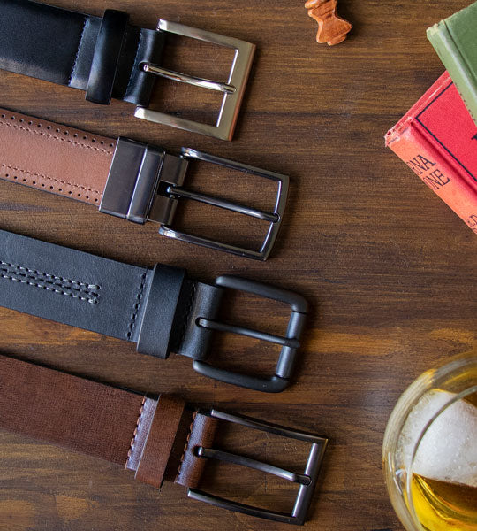 Men's leather belts in various colours and styles on a wooden background