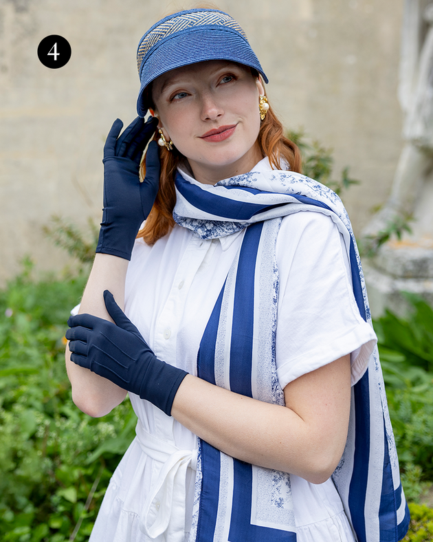 Woman wearing toile de jouy silk-like lightweight scarf with double border in navy in the garden with navy gloves and navy hat. 
