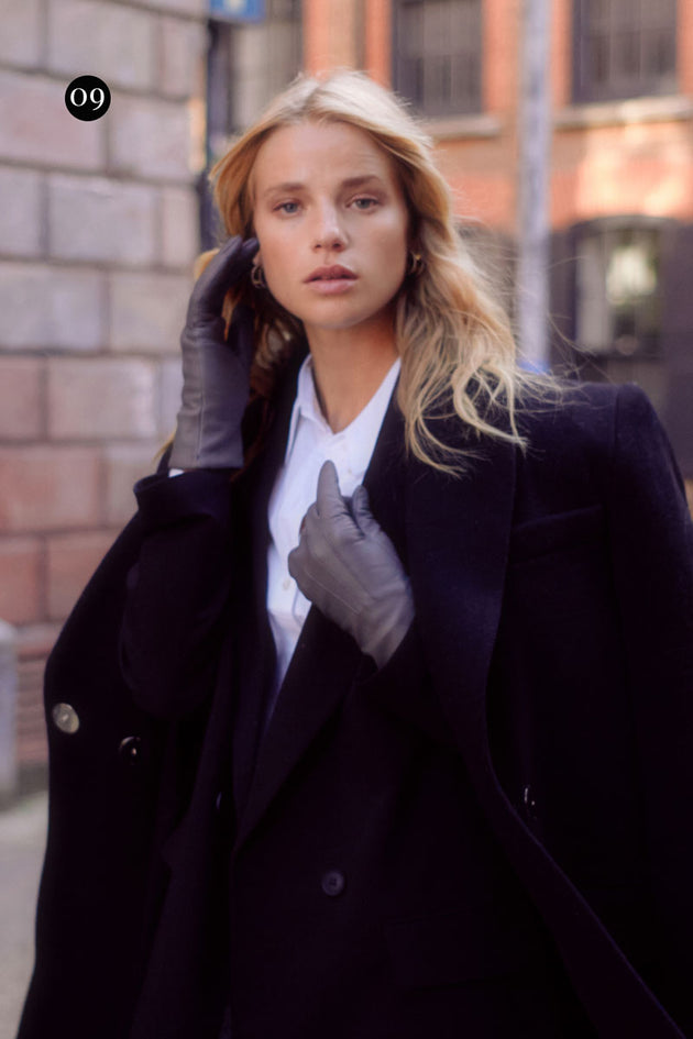 Woman wearing grey leather gloves with a black trench coat 