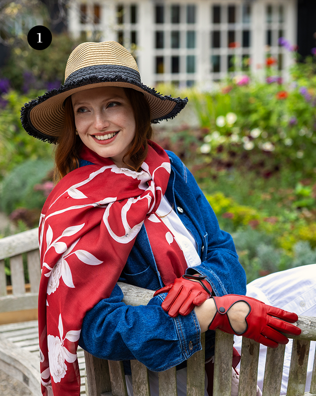 Woman wearing red silk-like scarf sitting on a bench. 