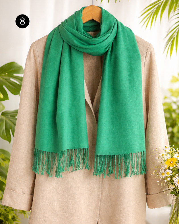 Women's plain pashmina shawl with tassels on a linen summer coat in emerald green with plain background. 